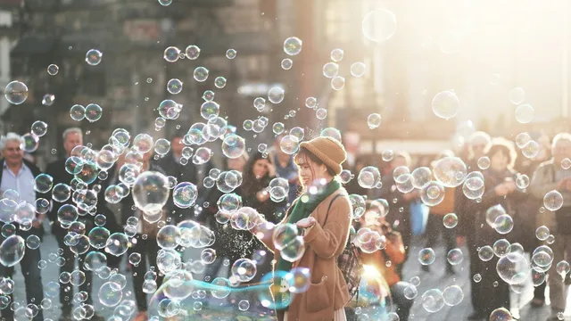 Una persona in mezzo a molte bolle di sapone in una strada.