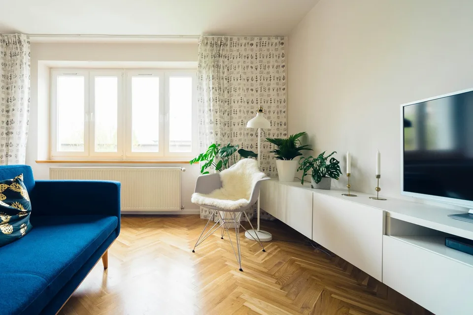 Un soggiorno con parquet a spina di pesce e finestre alte.