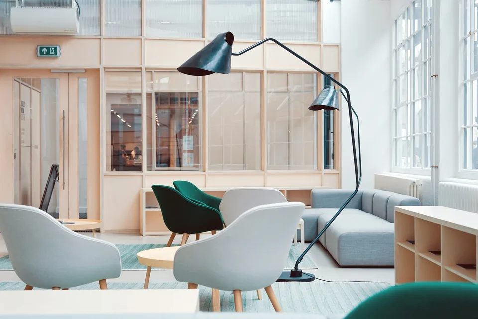 Una sala d'attesa con poltroncine chiare e una lampada ad arco.