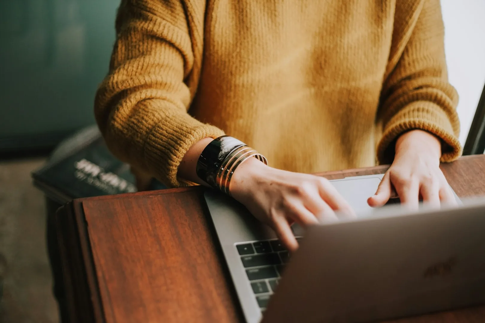 Una persona seduta a una scrivania di legno davanti a un computer portatile.
